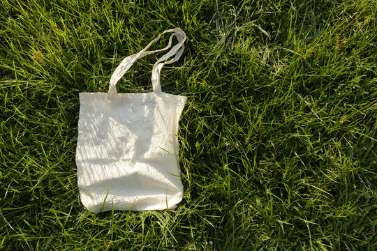 Blank reusable tote bag on green grass in sunlight ,sustainable lifestyle