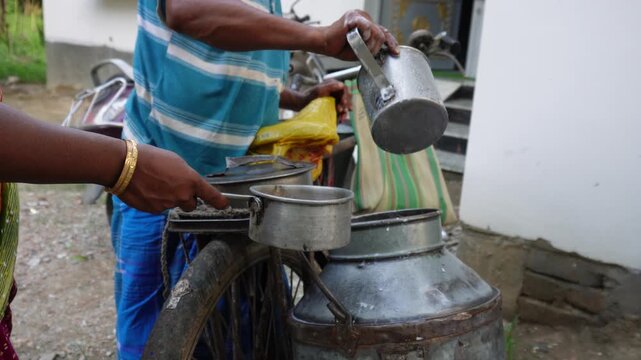 Milkman pouring fresh cow milk into aluminum pot for customer sale