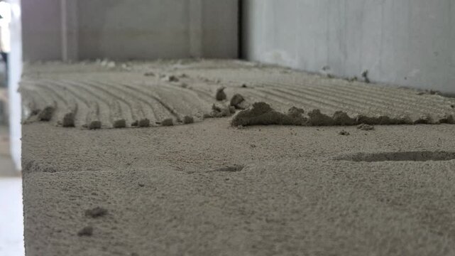 Placing another aerated concrete block onto the prepared mortar bed during interior wall construction, close up slow motion footage
