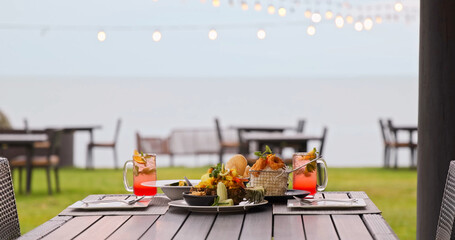 Obraz premium Tropical dinner table featuring pineapple fried rice and cocktails sitting at beachfront restaurant, evening string lights and ocean view, romantic dining, luxury travel lifestyle.