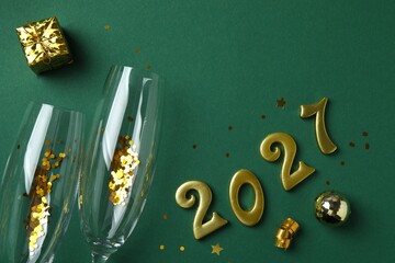 Golden numbers 2027 with festive decorations, including gift box, champagne glasses, stars and ornaments, preparation for the New Year's celebration. Happy New Year 2027