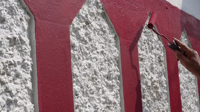Wall Painting Worker Applying Red Paint with Care