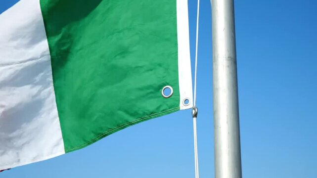 Italian National Flag Waving on Pole Against Clear Blue Sky