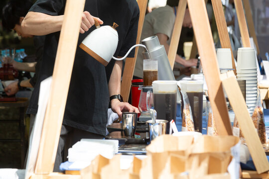 屋外のコーヒースタンドでコーヒー粉にお湯を注ぐ男性の手元