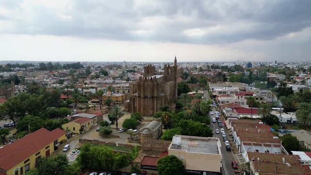 4K aerial drone shot of the historic Lala Mustafa Pasha Mosque in Famagusta capturing centuries of Gothic and Ottoman architecture from above in the rain.
