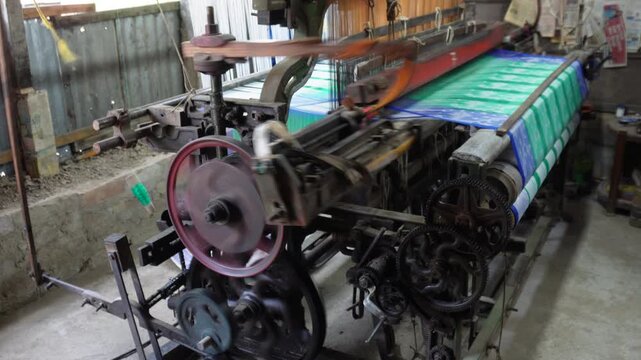 Power loom workers weaving fabric in textile factory