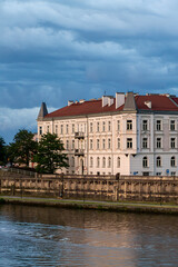 Obraz premium Historic riverside buildings under dramatic storm clouds at golden hour in Krakow city Poland