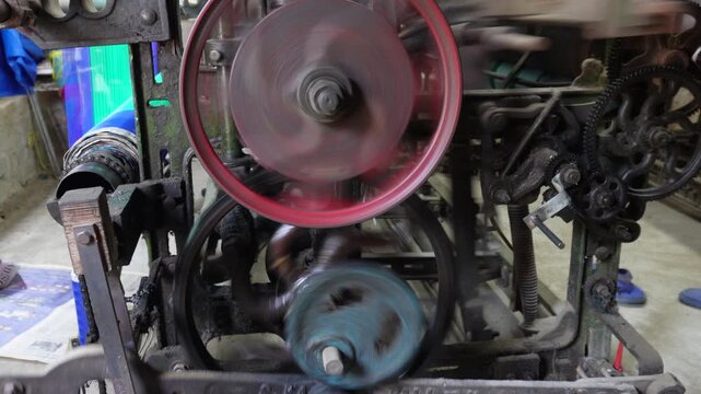 Vintage belt driven machine with red wheel in motion