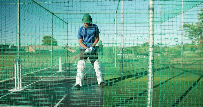 Male friends entering net cage hitting drives with bat during practice, bowler delivering ball