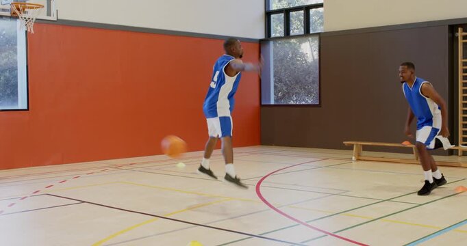 Starting drill african american partners bouncing basketball pass shooting layup rebounding in gym