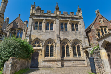 Fototapeta premium A historic light-grey stone building with gothic windows and a crenellated roof under a clear blue sky in Vicars' Close - Wells - Somerset - UK