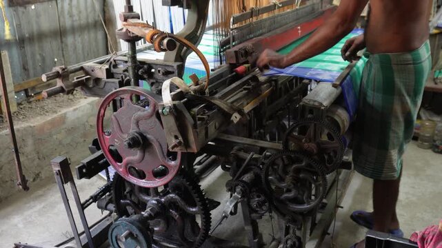 Power loom workers weaving fabric in textile factory