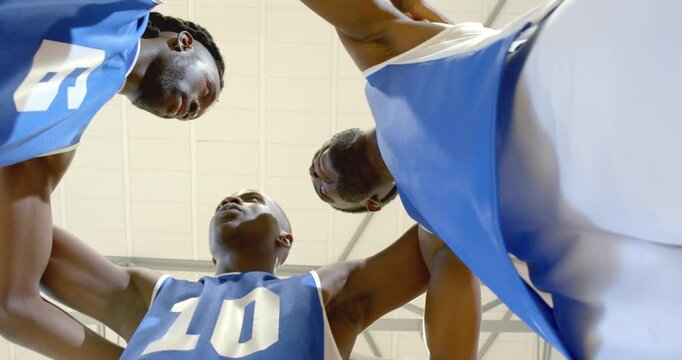 Delivering pregame pep talk three african american male players stacking hands in gym, jerseys