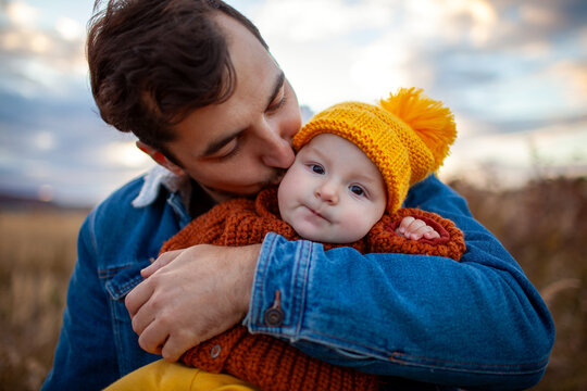 Father's day. Close up portrait of dad kissing his toddler daughter walking outdoors at sunset. Loving family. Man holds baby 