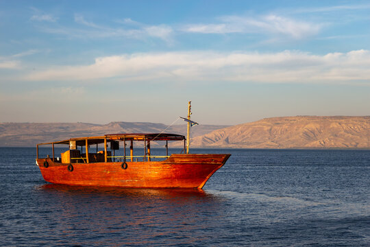 Traditional wooden boat sailing on the calm blue waters of the Sea of Galilee under a bright sky in Tiberias Israel