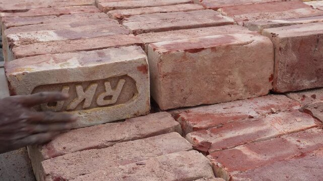 Hand stacking red bricks for construction