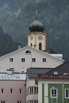 Traditional church tower with a clock and historic buildings in Kufstein, Tyrol.