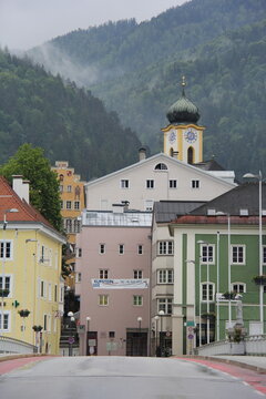 Traditional church tower with a clock and historic buildings in Kufstein, Tyrol.