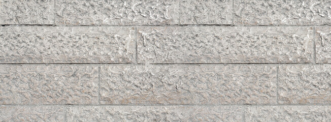 Fototapeta premium Grey rough stone wall displaying textured blocks surface