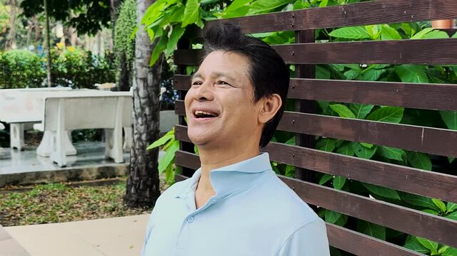 Relaxed happy carefree middle age old Asian man breathing the clean, unpolluted air in green park, wellness concept image of good summer, summer wellness, sunlight exposure for vitamin D synthesis