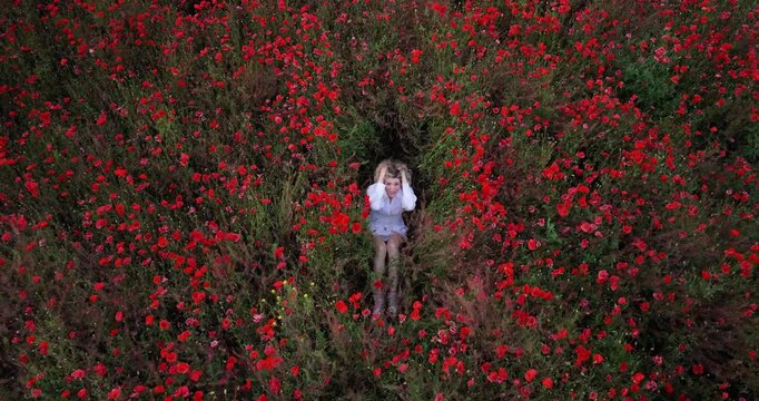 Young Woman Singing and Dancing While Sitting in Blooming Red Poppy Field Before Falling Back into Flowers