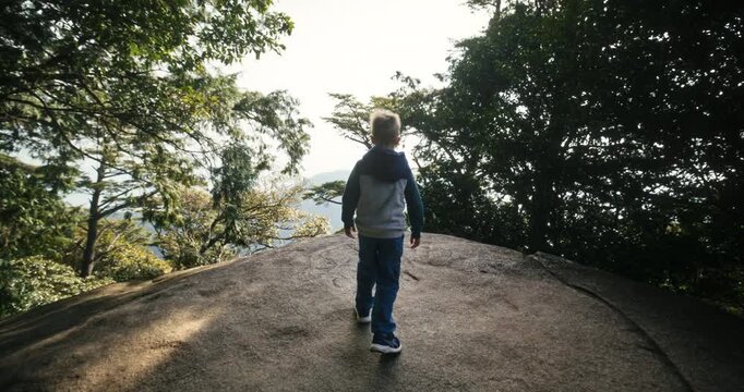 Boy Walking on Rock Outcrop Toward Forest Overlook in Japan - Slow, Steady Cam Shot