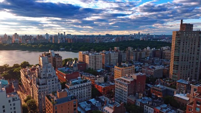 Flight over the blocks with lots of greenery near Central Park. New York City panorama at sunset from drone. Cloudy sky over the scenery.