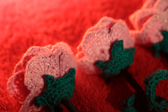 Soft pink wool flowers arranged on deep red fabric or surface