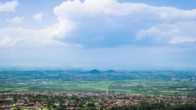 Town Plovdiv with houses and fields against backdrop of Rhodope Mountains and hills covered with forests and cloudy sky