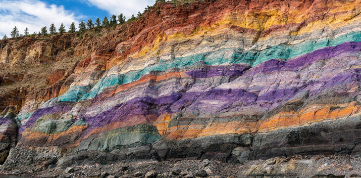 Geological layers of a colorful cliff face showing sedimentary rock strata in various hues with sedimentary colorful geological formation landscape mountain environment geoscience