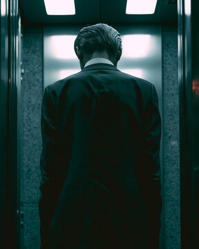 Back of Office Worker Standing in Elevator, Slumped Posture, Harsh Fluorescent Light, Urban Fatigue