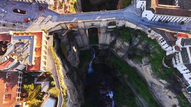 Puente Neuvo bridge aerial view - High angle drone video of iconic 18th-century stone arch bridge in Ronda, Spain. Shot starts almost directly above bridge and zooms out tracking the bridge.