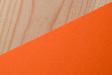 Fototapeta premium Bright orange paper contrasts with light wooden surface beautifully