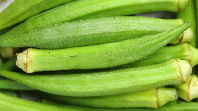 Pile of fresh raw okra pods rotating slowly. Top view shot