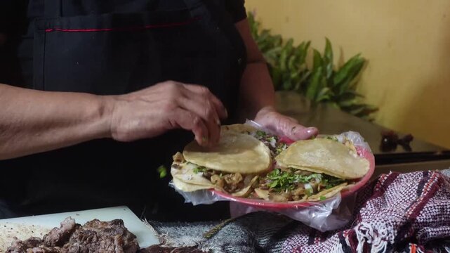 Close-up of hands preparing fresh street tacos with meat, onion and cilantro