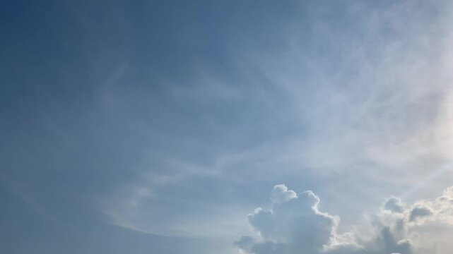 4K bright sun shining through dramatic clouds above Jakarta, Indonesia. Upward view with soft lens flare, vivid blue sky and natural light, ideal for weather, energy, inspiration and nature themes.