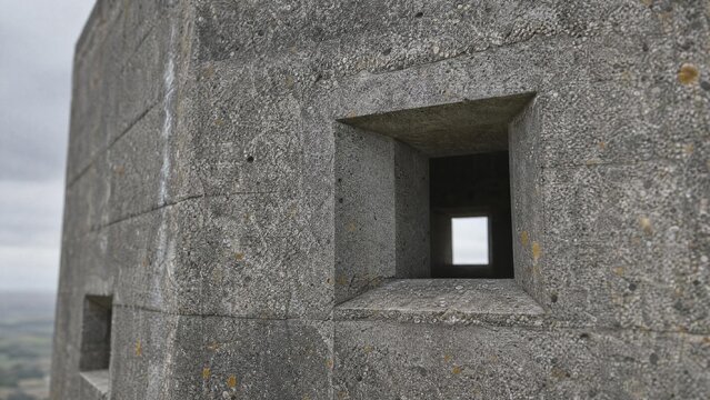 Close-up of a grey concrete blockhouse, square firing port and rough textured surface.