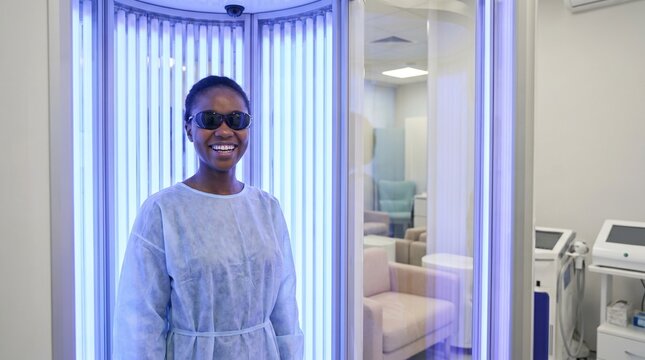 Young Woman Smiling in Phototherapy Booth, Treating Psoriasis with UVB Light, Medical Treatment for Skin Condition, Advanced Psoriasis Care in Clinic