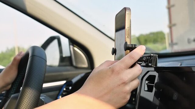 Young woman types message on smartphone while holding steering wheel in traffic jam, showing distracted driving risk in car