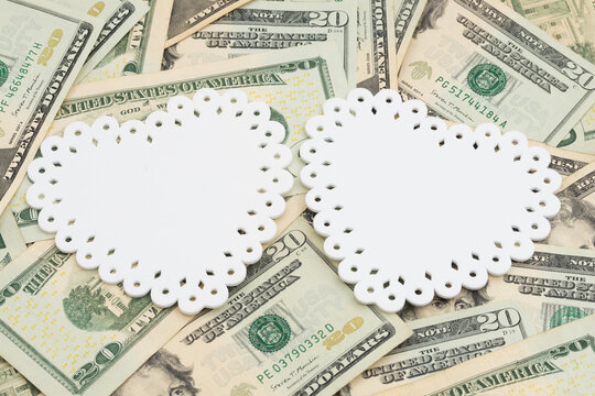 Two blank white hearts on twenty dollar bills for cost of relationships