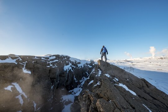 Mountain hiker stands at Continental Rift between North American and Eurasian Plate, Mid-Atlantic Ridge, Rift Valley, Silfra Rift, Krafla, North Iceland, Iceland
