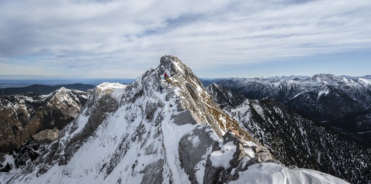 Three mountaineers on a rocky snowy ridge, hiking trail to Ammergauer Hochplatte, view of mountain panorama, behind summit Ammergauer Hochplatte, in autumn, Ammergauer Alps, Bavaria, Germany