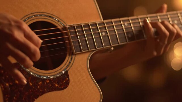 A musician playing acoustic guitar, strumming strings and pressing frets, creating music, instrumental performance, warm lighting