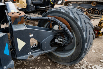 Fototapeta premium Heavy duty steering knuckle and hydraulic drive motor assembly on an industrial wheel loader chassis featuring high pressure fluid lines and rubber tire