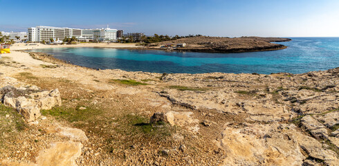 Turquoise water of Vathia Gonia beach bay protected by rocky cape in winter morning. Empty sand coast with white resort hotels during sunny low season, panoramic view, Ayia Napa, Cyprus. © Vlad Rakin