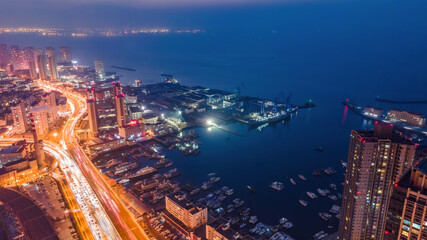 Naklejka premium Night View of Coastal City Port and Busy Road