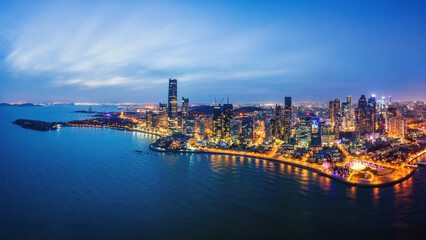 Obraz premium Coastal City Skyline Illuminated at Dusk by the Sea