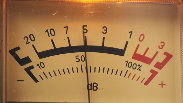 A macro view displays an analog VU meter needle oscillating rhythmically on a yellow scale against a backlit panel. Concept of retro music production, audio levels, and high fidelity sound.