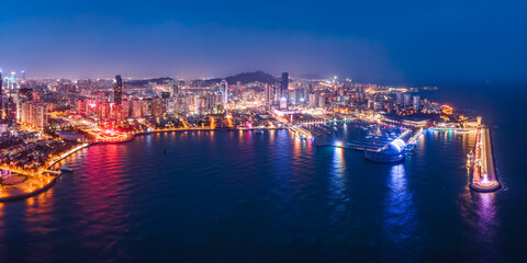 Obraz premium Nighttime Coastal Cityscape With Marina And Illuminated Buildings