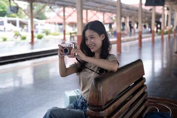Obraz premium Asian tourist woman taking photos with vintage camera at train station platform